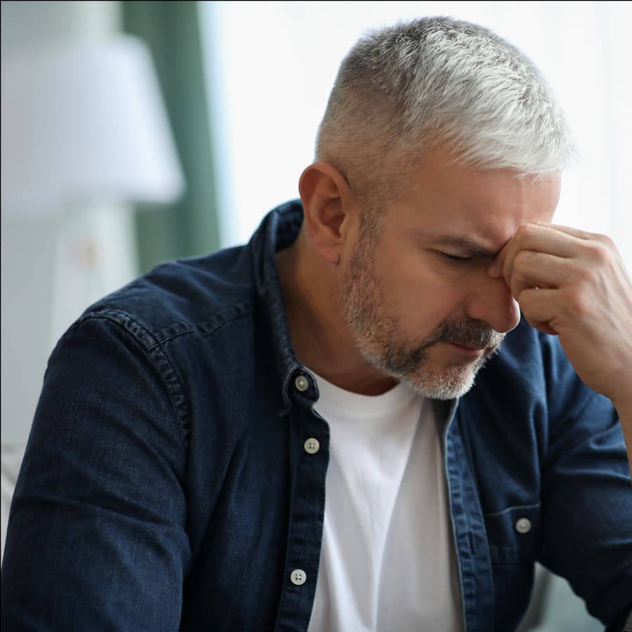 A man sitting at home with his hand to his face